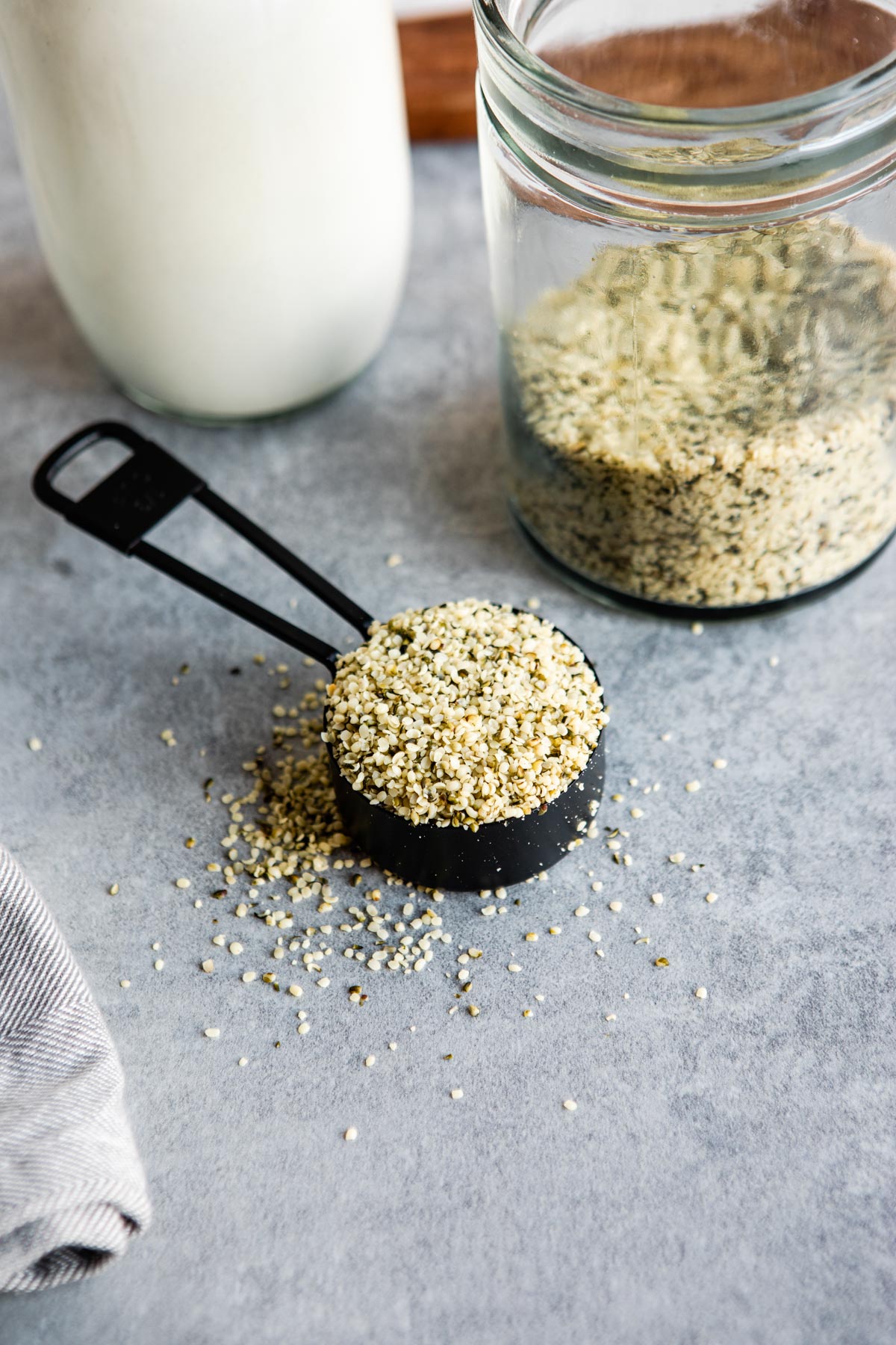 a black measuring cup with hemp seeds.