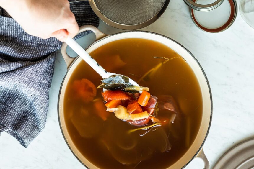 Spoon with carrots, celery and onions that have been cooked into a stock.