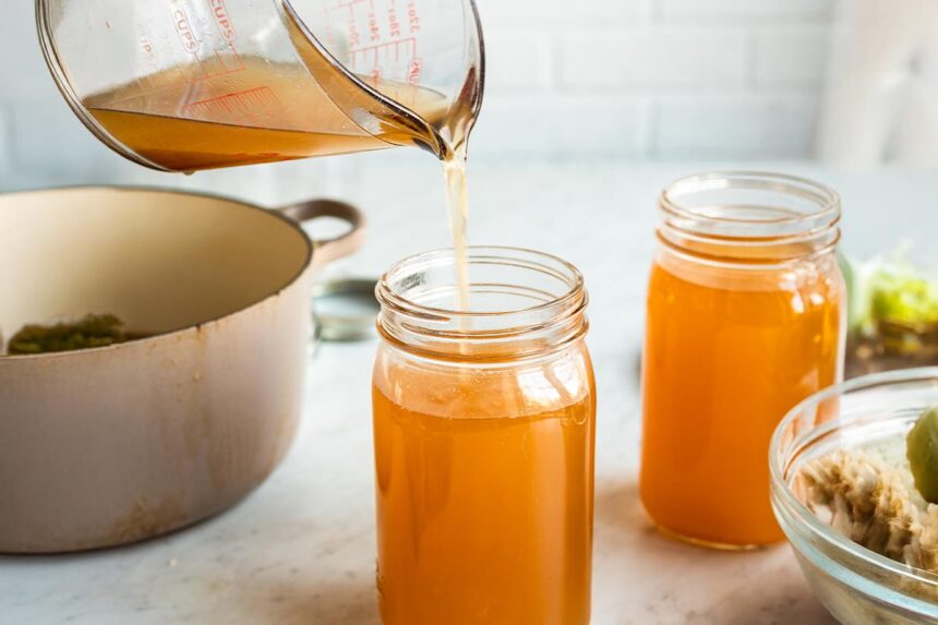 Pouring vegetable stock into mason jar.