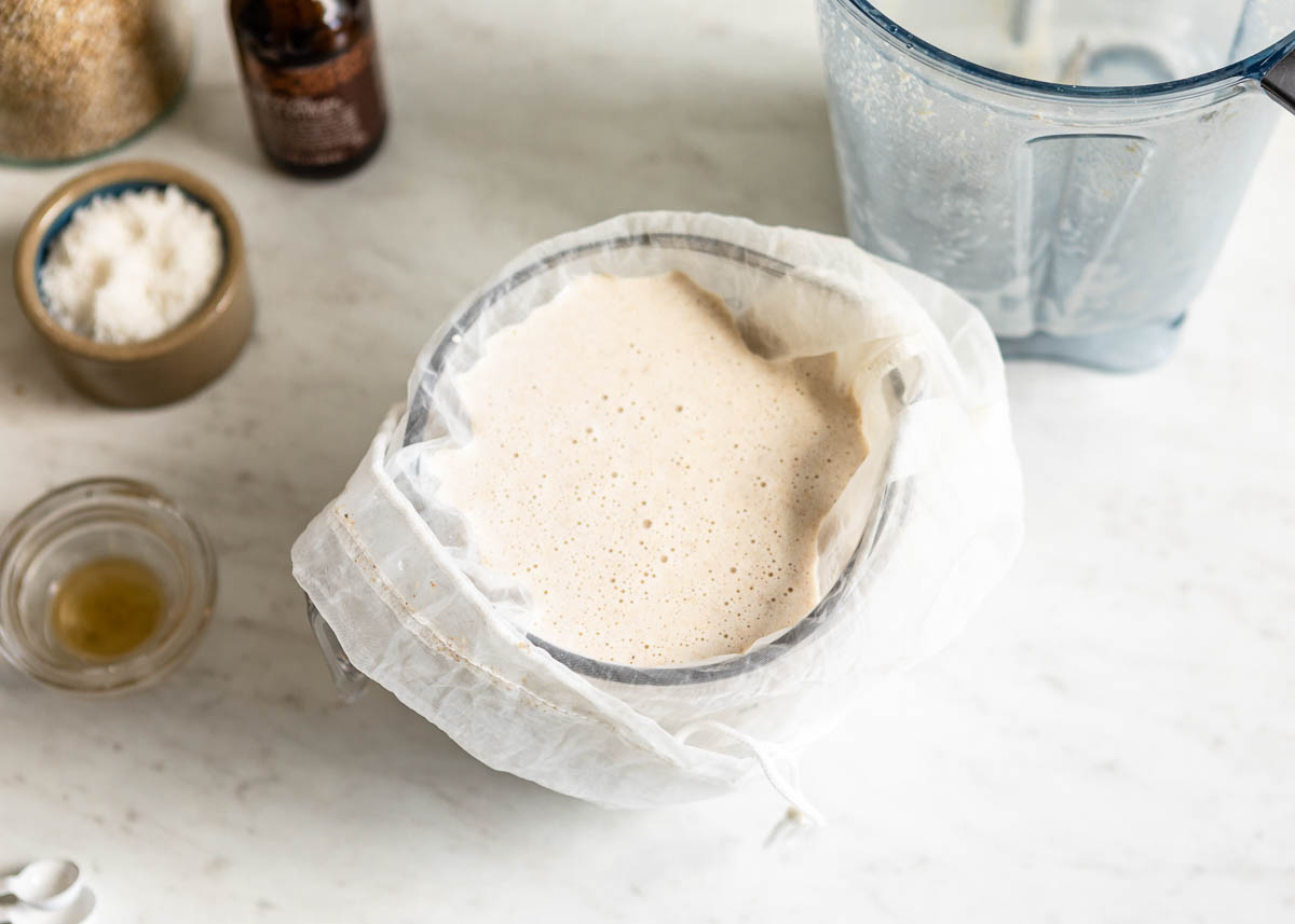 Straining the pulp from this homemade oat milk recipe with a cheese cloth.