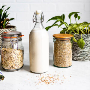 Bottle of oat milk recipe with rolled oats and water next to it