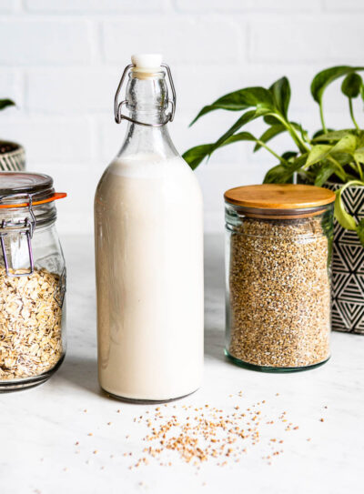 Bottle of oat milk recipe with rolled oats and water next to it