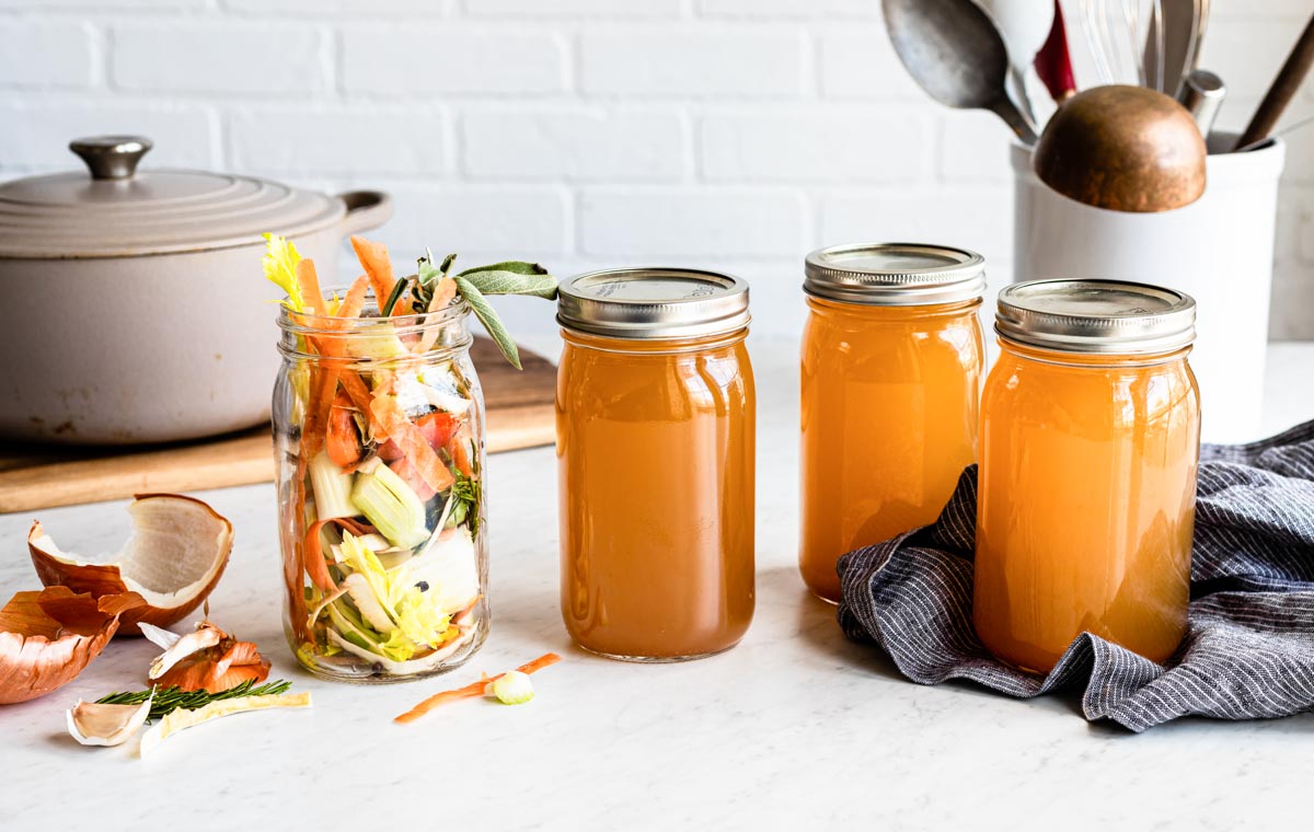 3 mason jars of homemade vegetable stock and 1 mason jar of vegetable scraps.