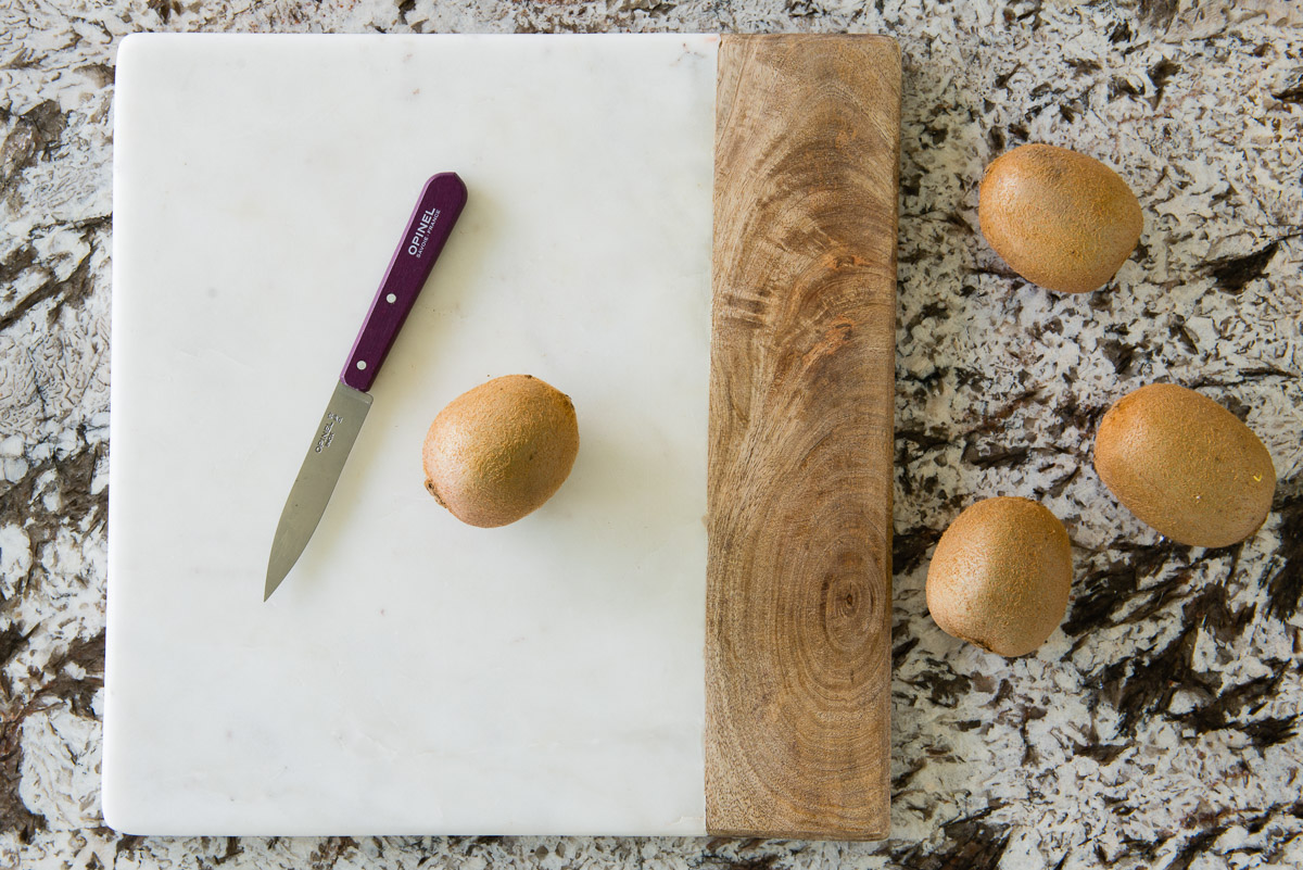 Fresh kiwis on a kitchen counter with a knife and cutting board