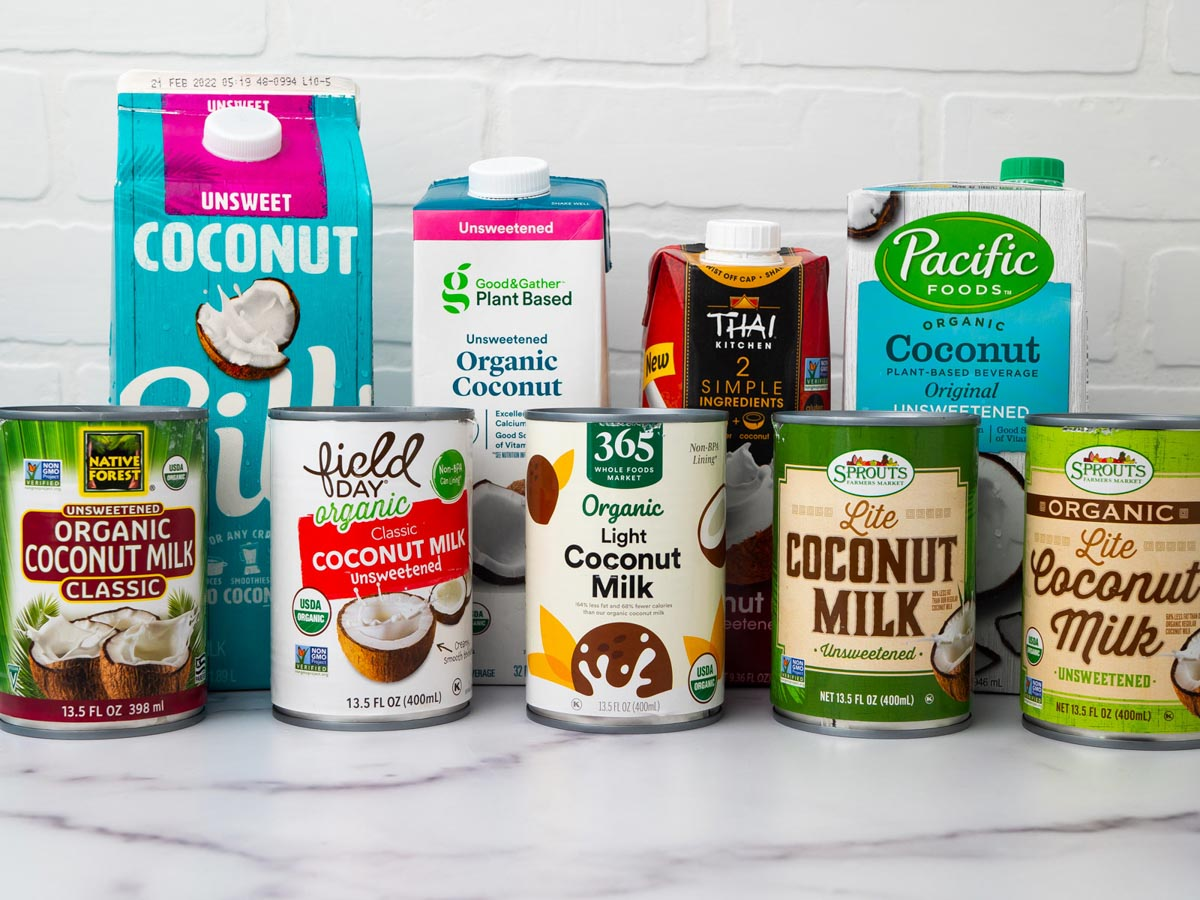 9 different milk brands tested to find out the best coconut milk brand, sitting on a marble countertop.