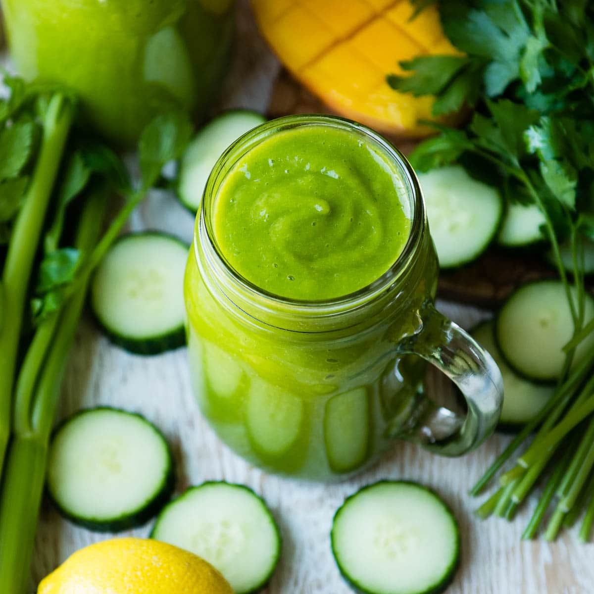 Refreshing immune boosting smoothie in a jar surrounded by cucumbers.