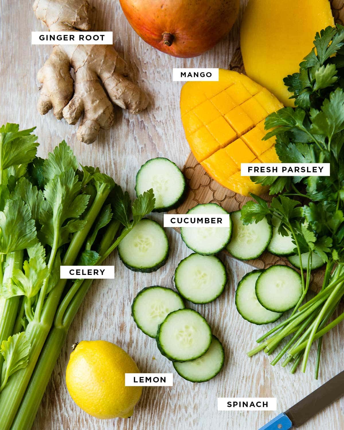 ingredients in a green smoothie including ginger root, mango, fresh parsley, cucumber, celery, lemon and spinach
