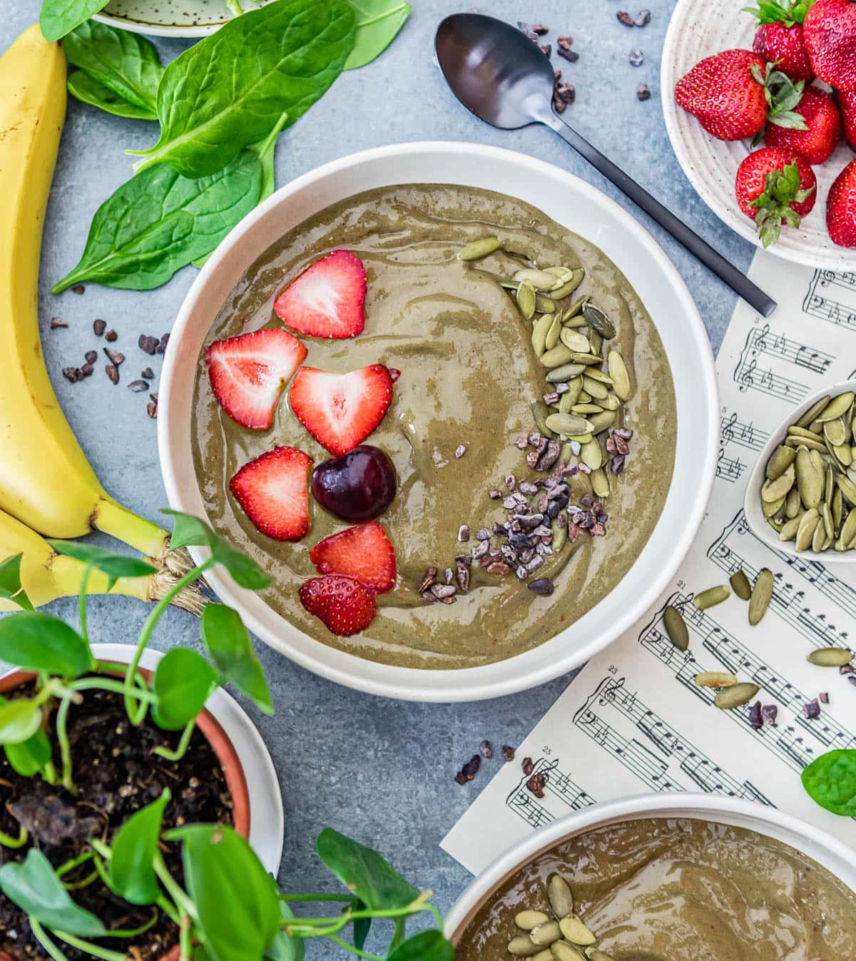 Overhead photo of an iron-rich smoothie bowl topped with fresh strawberries, cherries, pumpkin seeds and maca.
