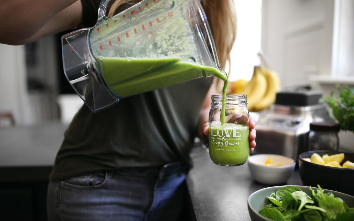 Pouring fresh green smoothie in a jar