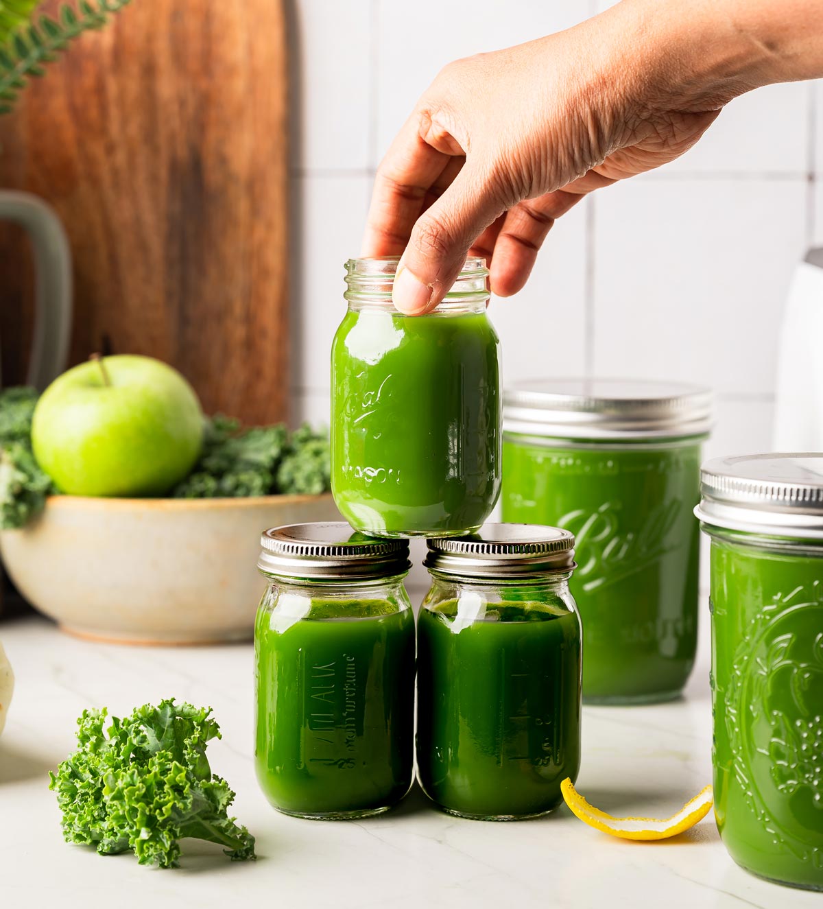 Mason jars of fresh bright green juice being stacked on the counter