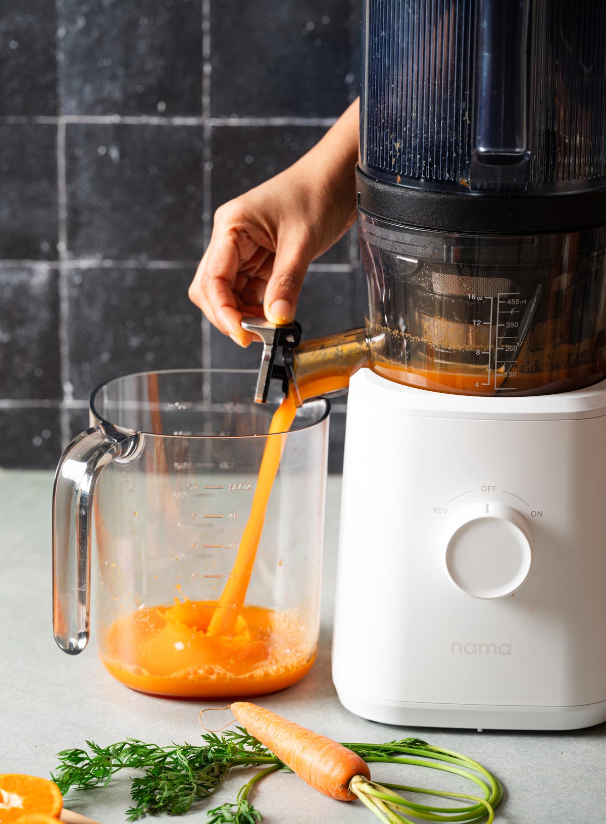 Pouring fresh juice from a juicer spout into a container