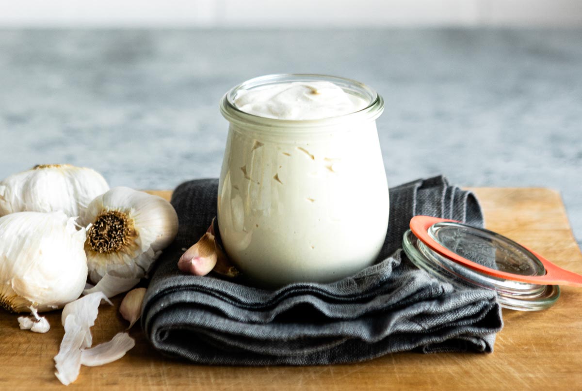 garlic lemon aioli in a glass jar on a black towel.