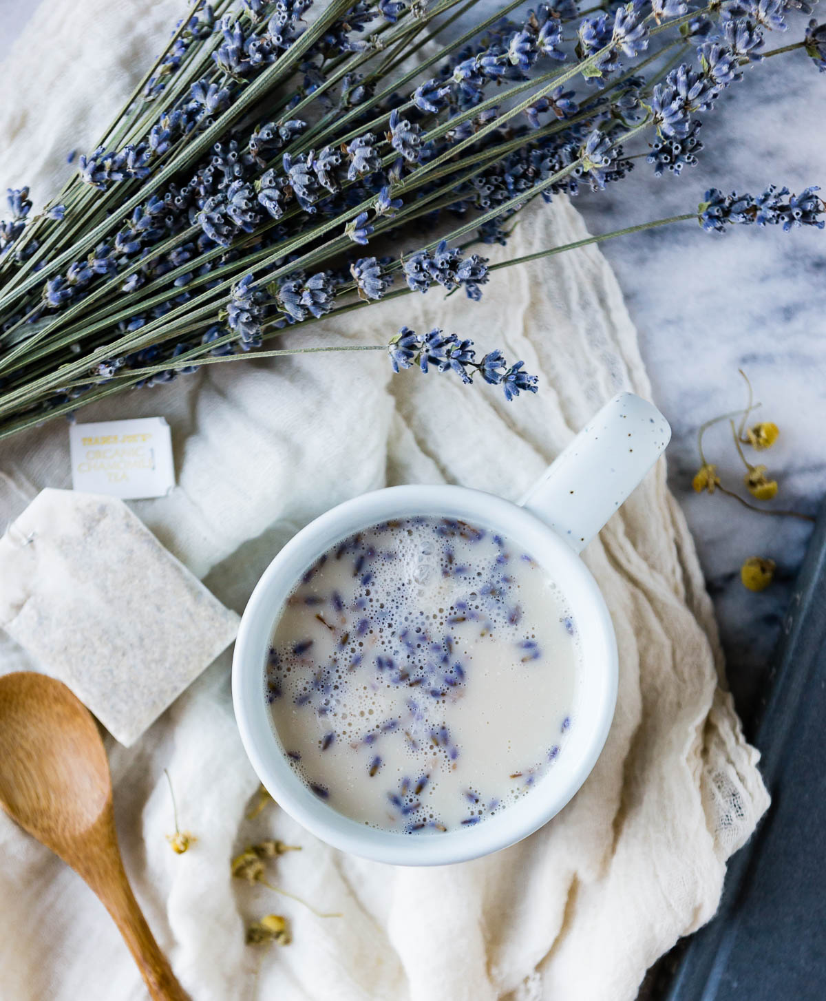 lavender herbal tea for sleep in white mug with dairy free milk next to fresh bunch of lavender.