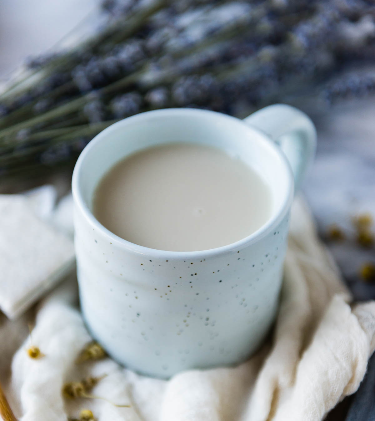 white speckled mug of dairy free milk + chamomile tea.