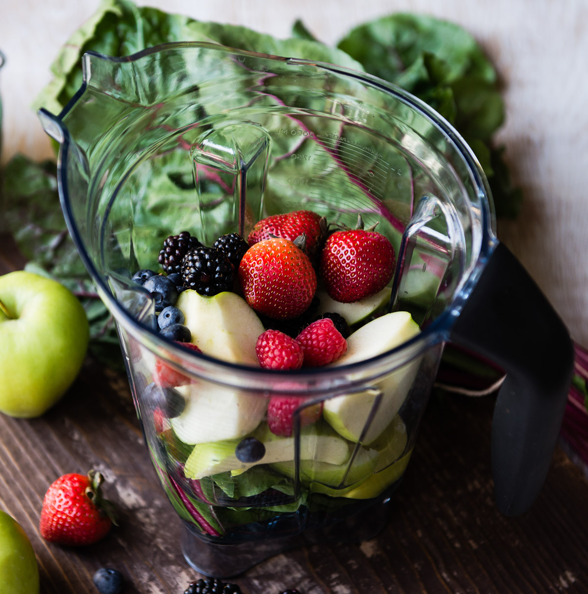 A blender container filled with lower sugar berry options for smoothies.