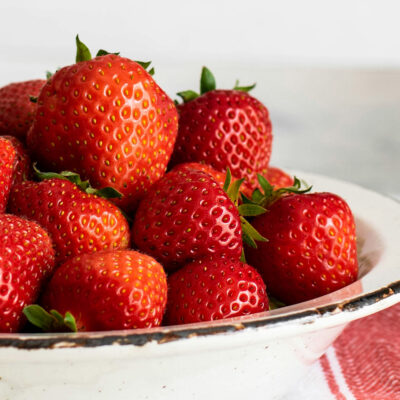 Fresh strawberries in a white dish.