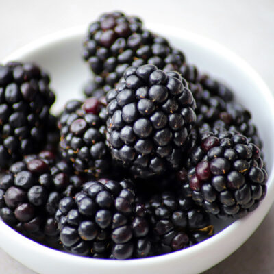 Small serving of fresh blackberries in a shallow, white dish.
