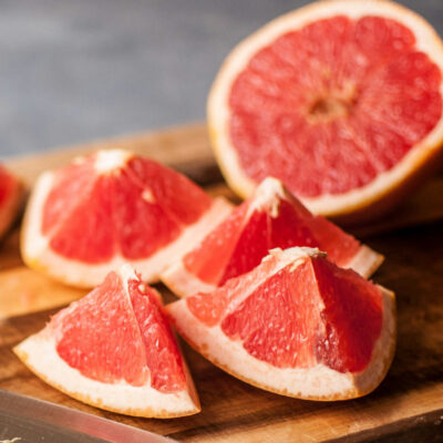 Fresh cut grapefruit on a wooden cutting board.