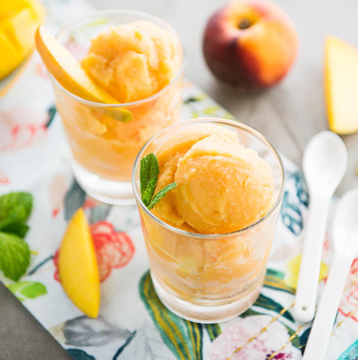 2 glasses of mango sorbet topped with mango slices and mint.
