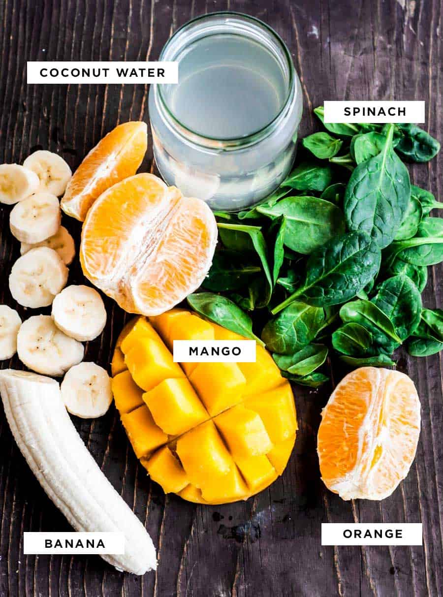 ingredients for a tropical smoothie including spinach, mango, banana and orange.