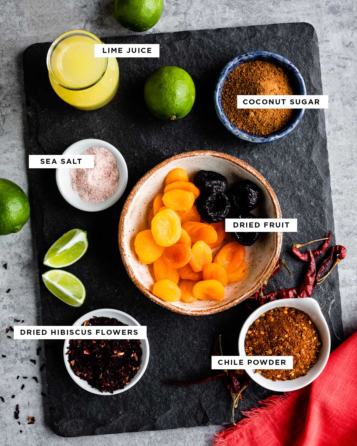 ingredients for the best chamoy sauce including lime juice, coconut sugar, dried fruit, sea salt, dried hibiscus flowers and chile powder.