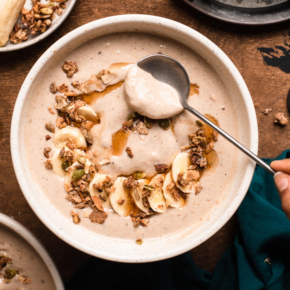Spoon scooping maple oat smoothie from a bowl.