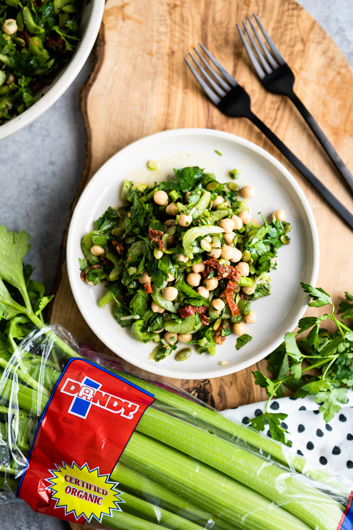 marinated celery salad on white plate surrounded by fresh parsley and celery stalks.