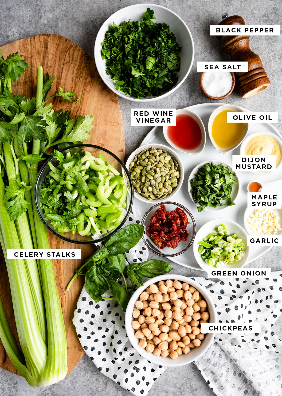 labeled ingredients including black pepper, sea salt, red wine vinegar, olive oil, dijon mustard, maple syrup, garlic, celery stalks, green onion and chickpeas.