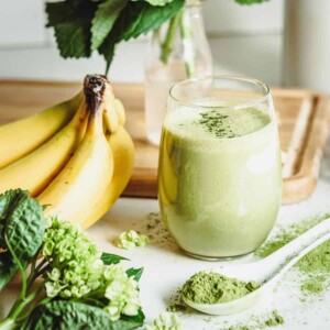 A vanilla matcha smoothie surrounded by fresh ingredients.