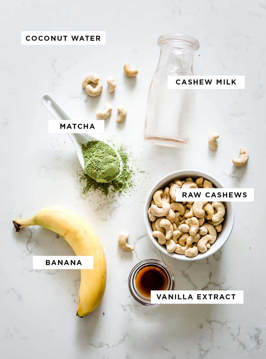 labeled ingredients for a green tea smoothie including coconut water, cashew milk, matcha, raw cashews, banana and vanilla extract.