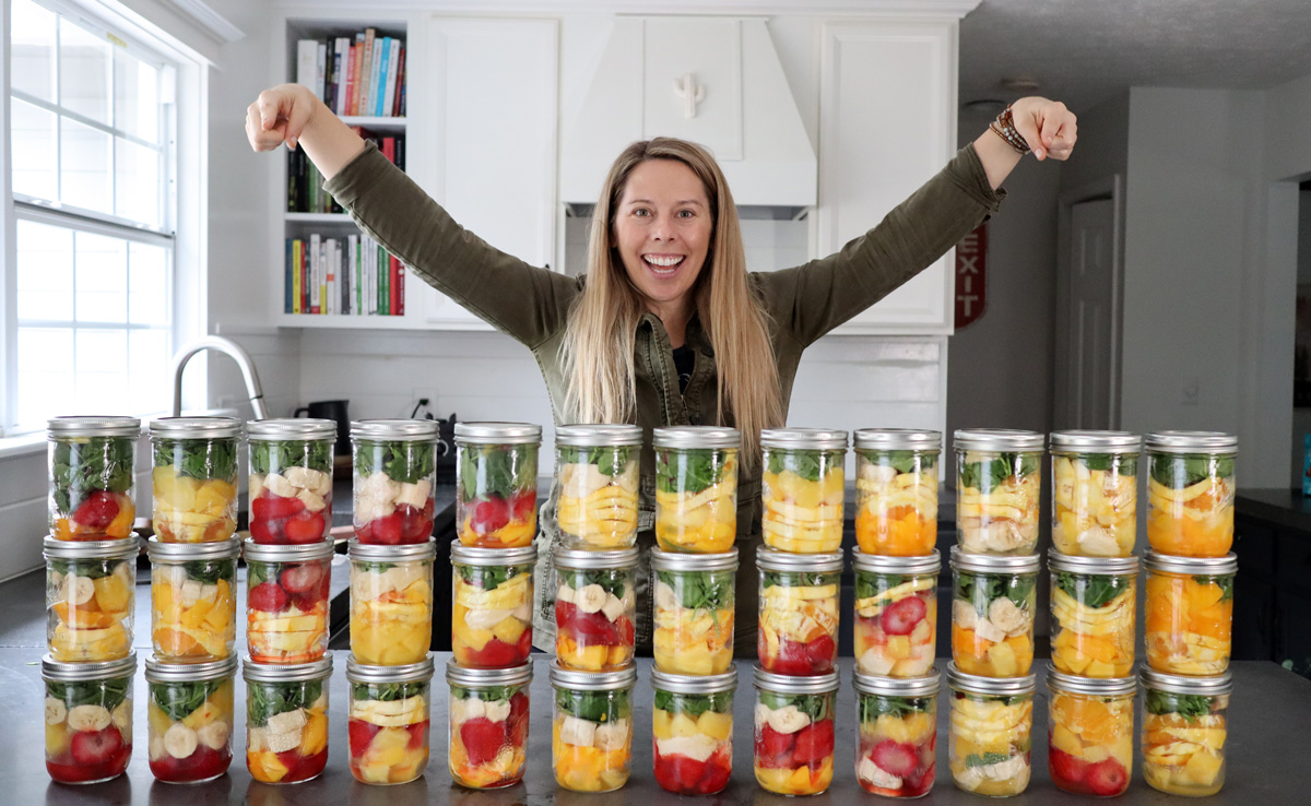 Women in kitchen with 30 frozen smoothie packs in mason jars.