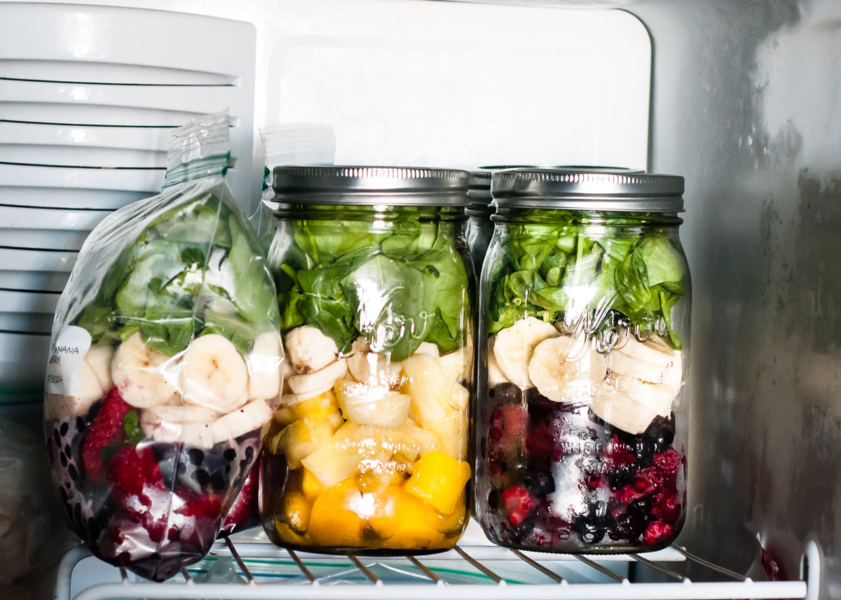 Freezer with smoothie packs in mason jars and bags stacked on shelf.