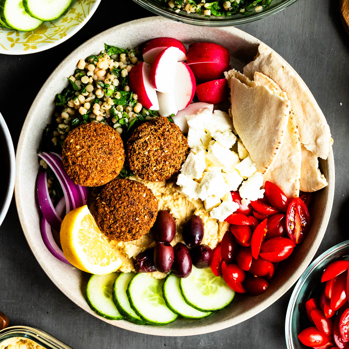 Mediterranean falafel bowl with a rainbow of vegetables, vegan feta and herbed couscous.