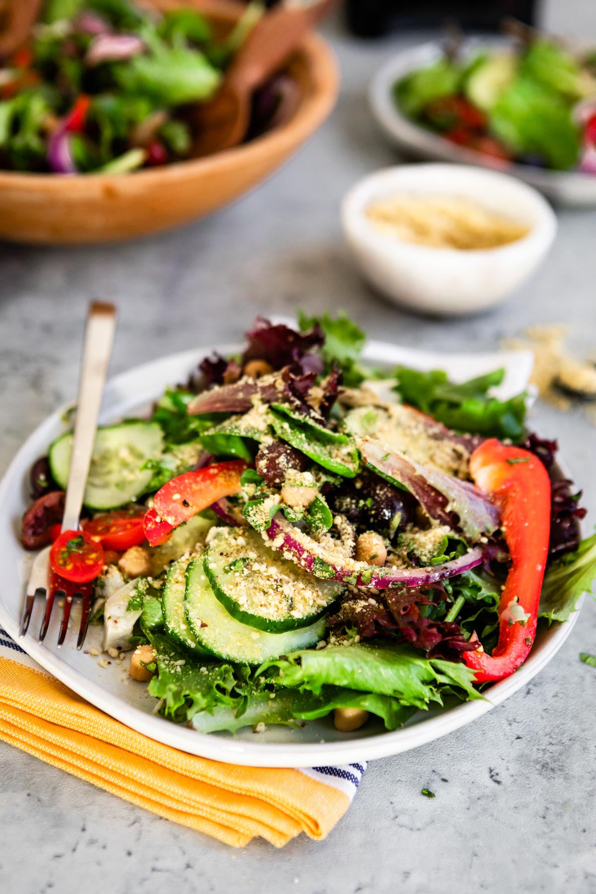 greek salad recipe with vegan ingredients, topped with vegan cheese sprinkle.