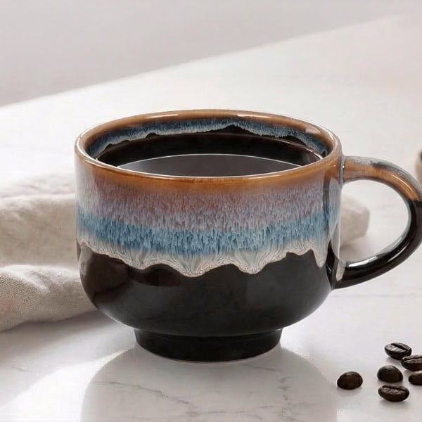 Ceramic coffee mug with blue and brown glaze on a white surface.