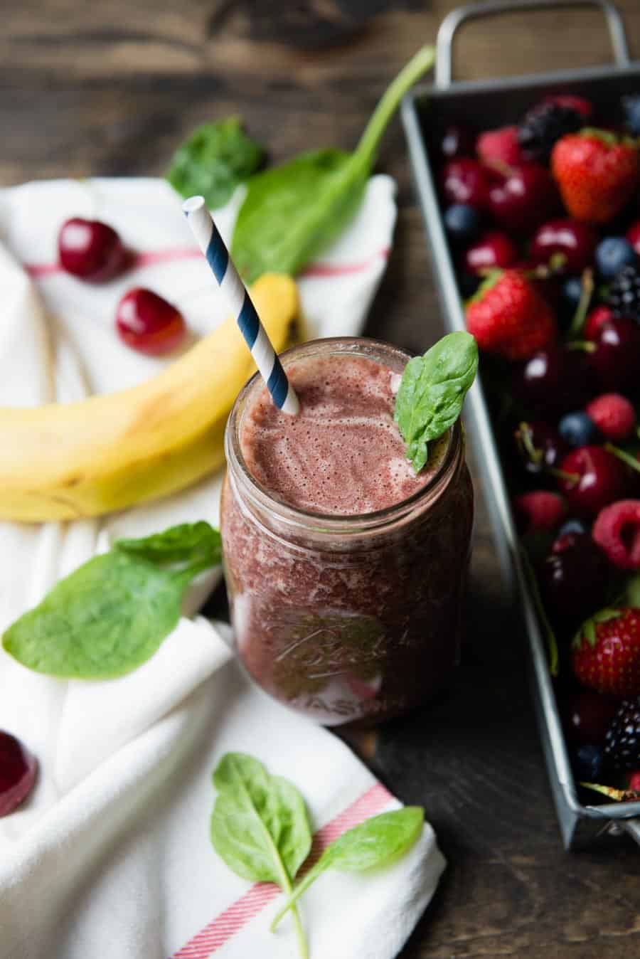 Mixed berry smoothie in a glass jar with a paper straw.