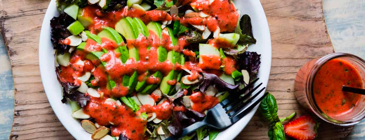 mixed greens salad with avocado on top and red/pink dressing