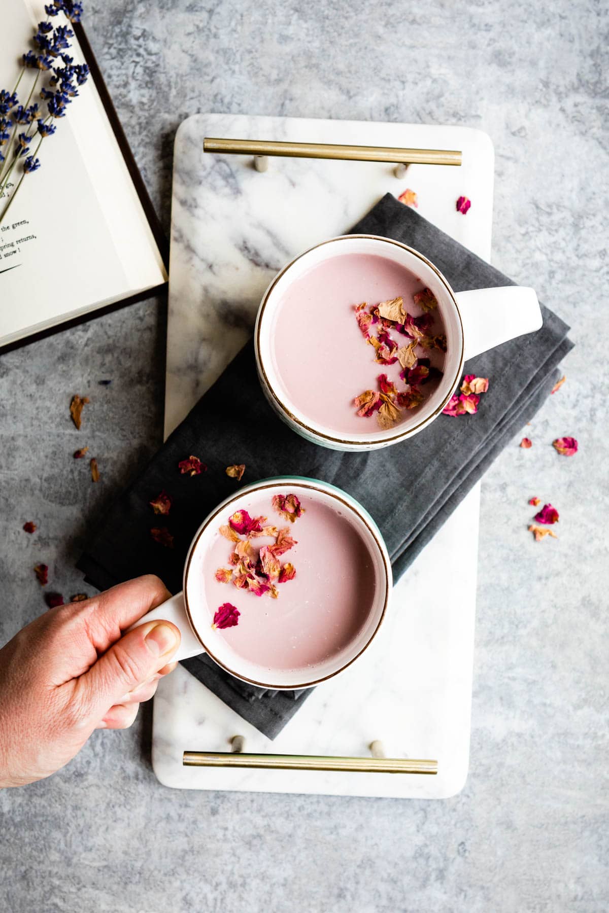 2 mugs of pink moon milk topped with dried flowers.
