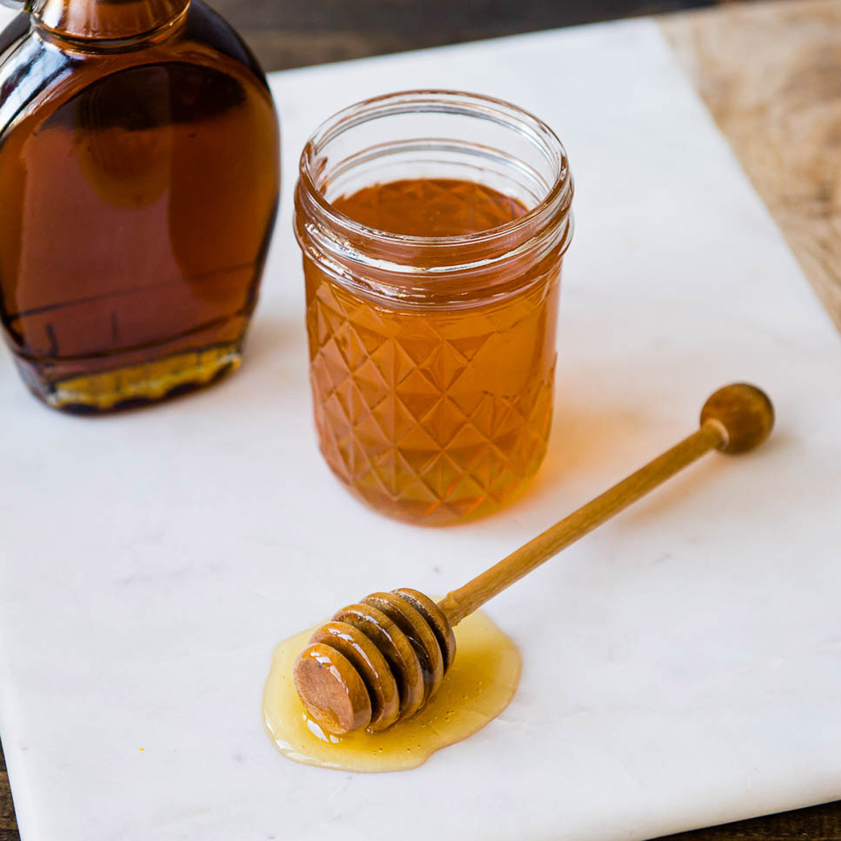 examples of natural sweeteners including bananas, honey in a glass jar, maple syrup and dates.