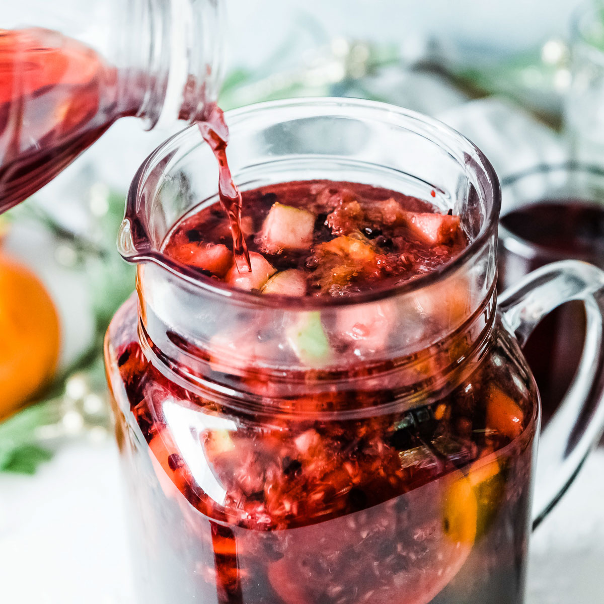 A person preparing non-alcoholic sangria in a glass jug