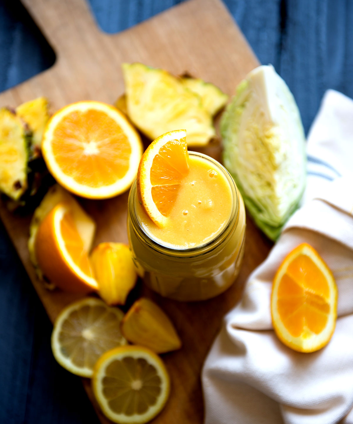 Glass cup with orange cabbage smoothie and sliced orange wedge on top.