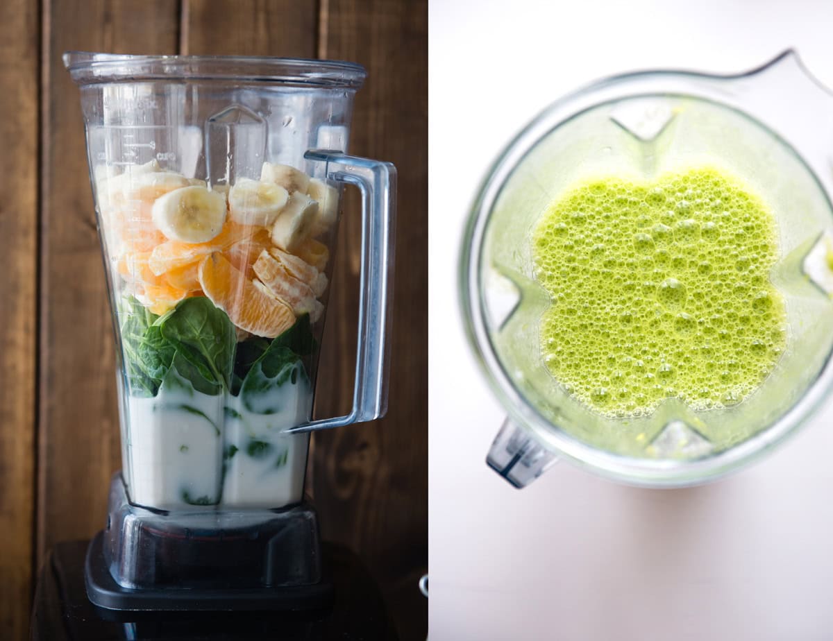 Fresh orange banana smoothie in blender with green leafy ingredients.