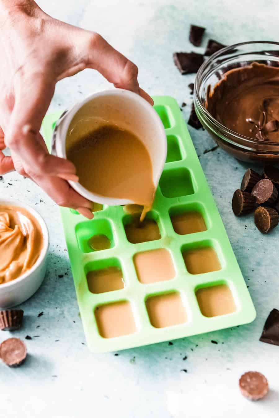 pouring light brown mixture into green silicone squares to freeze.