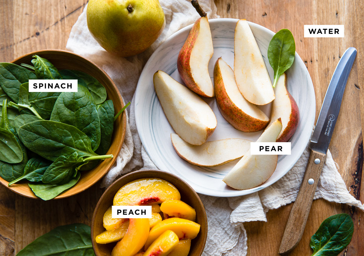 labeled ingredients for a pear smoothie recipe including water, pear, spinach and peaches.