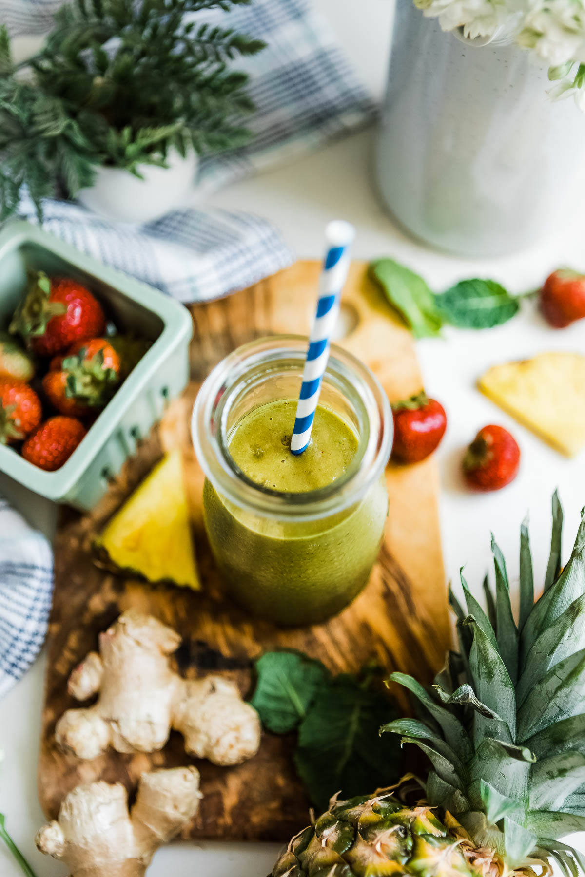 A pineapple ginger smoothie in glass jar with a straw.