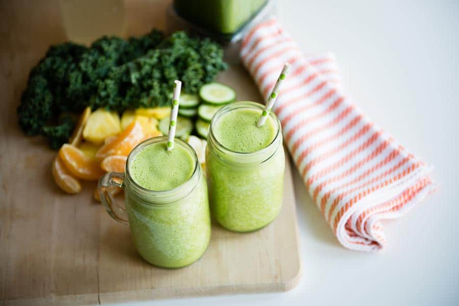 2 jars of pineapple green smoothie with paper straws.
