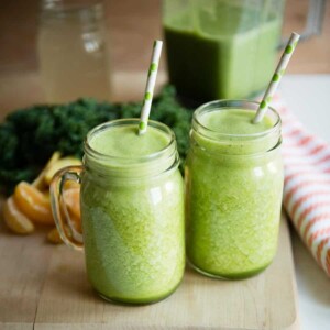 2 containers of pineapple green smoothie with paper straws.