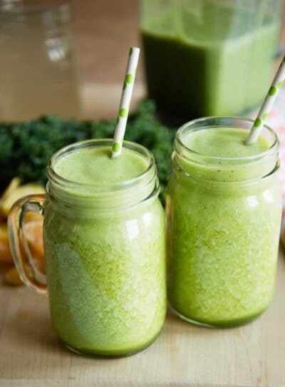 2 containers of pineapple green smoothie with paper straws.