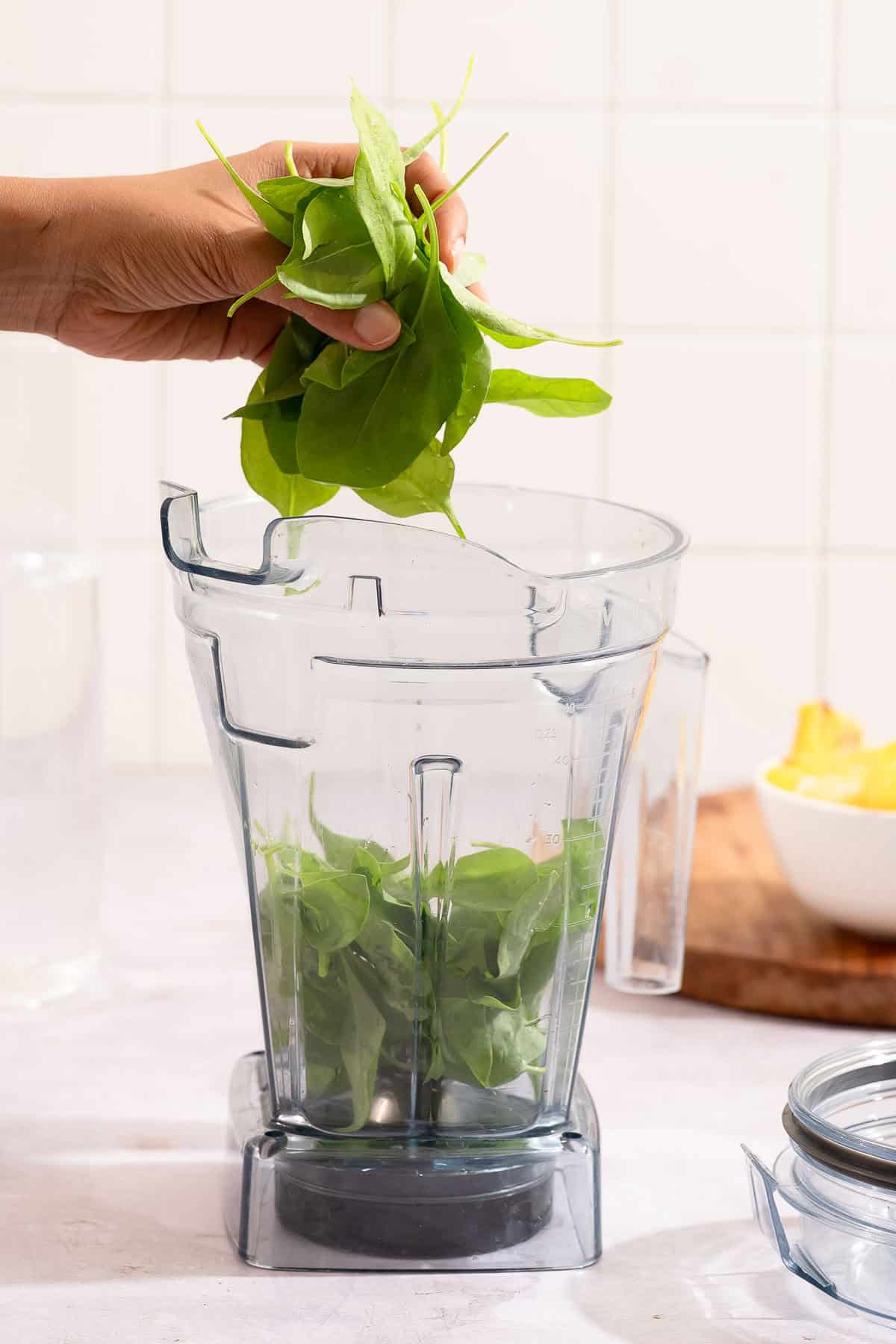 Fresh spinach being added to a blender for smoothie.