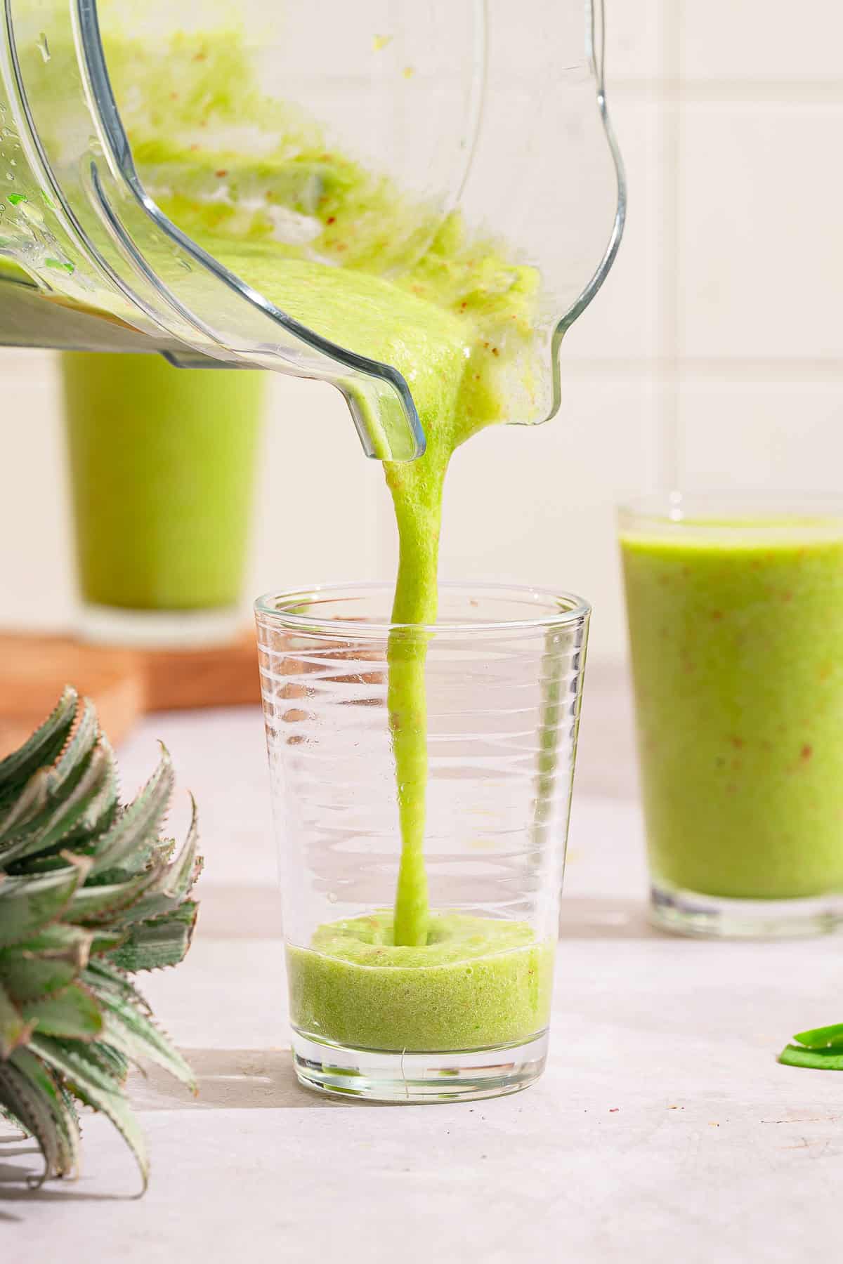 Spinach smoothie being poured into a glass
